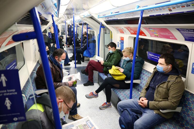 People wearing protective face masks commute in a Victoria line underground train in London. Reuters