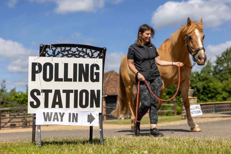 A woman walks a horse near a polling station in Hambledon. Bloomberg