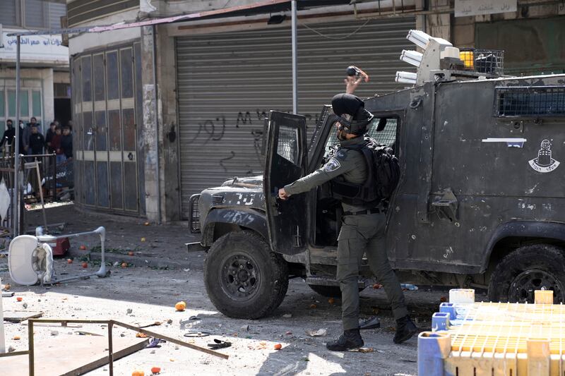 An Israeli officer throws teargas at Palestinians in Nablus. AP 