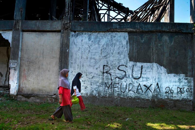 Women walk by a building dedicated to the 2004 Indian Ocean earthquake and tsunami that killed more than 220,000 ahead of the 15th anniversary on December 26, in Banda Aceh. AFP