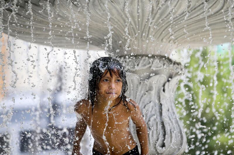 A child seeks respite from the summer heat in a water fountain at a park in Manila, Philippines. AP Photo