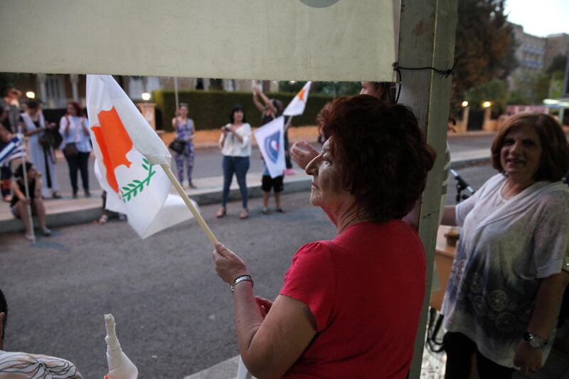 A woman waves a Cypriot flag during a protest against positions put forward by Greek Cypriot president Nicos Anastasiades in reunification talks, at the Ledra Palace checkpoint in the UN-controlled buffer zone in Nicosia on July 6, 2017. Yiannis Kourtoglou / Reuters