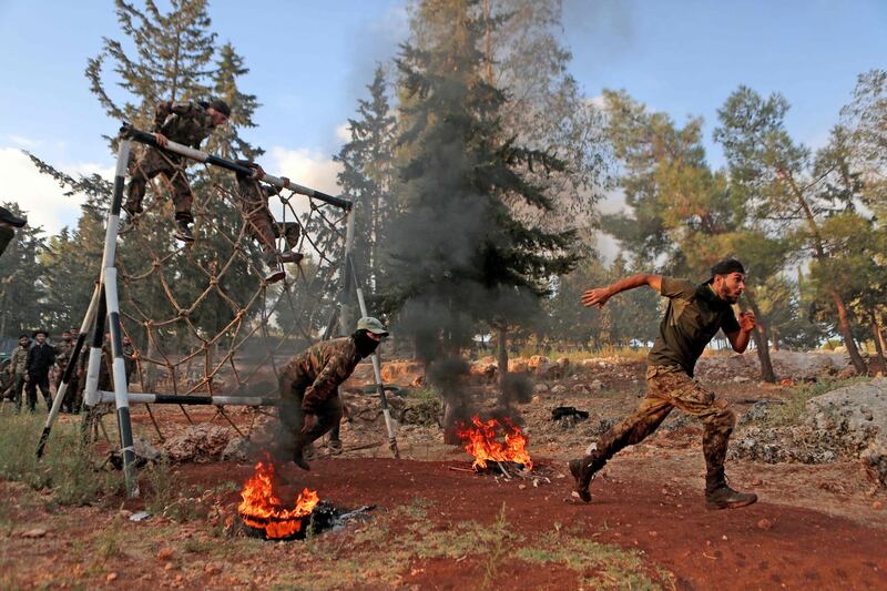 Members of the Hayat Tahrir Al Sham militant group in Syria run an obstacle course as they train for war. AFP