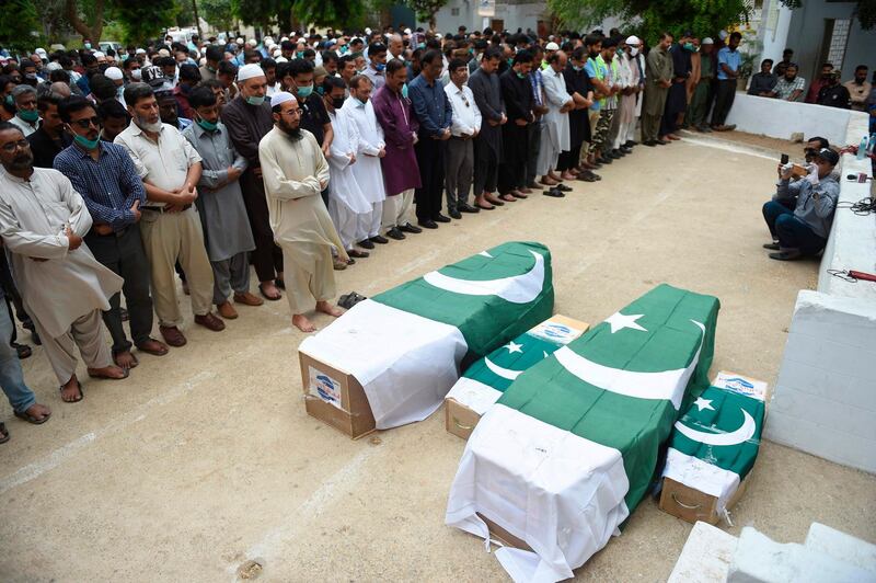 Mourners offer funeral prayers beside the coffins of the victims of the Pakistan International Airlines (PIA) plane crash in Karachi on June 2, 2020. The Pakistan International Airlines (PIA) plane came down among houses on May 22 after both engines failed as it approached Karachi airport, killing 97 people on board. Two passengers survived.  / AFP / Rizwan TABASSUM
