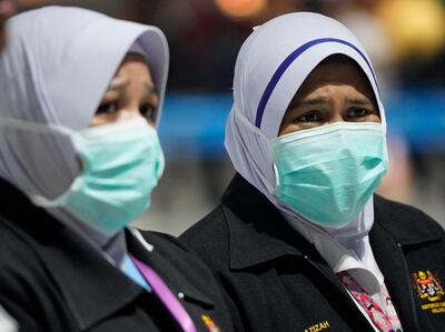 Health officials wear face masks at an inspection site at the Kuala Lumpur International Airport in Sepang, Malaysia, Tuesday, Jan. 21, 2020. Countries both in the Asia-Pacific and elsewhere have initiated body temperature checks at airports, railway stations and along highways in hopes of catching those at risk of carrying a new coronavirus that has sickened more than 200 people in China. (AP Photo/Vincent Thian)