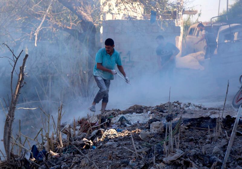 Syrians use dirt to put out a fire at the scene of a reported air strike in the district of Jisr al-Shughur, in the Idlib province, on September 4, 2018. - Russian warplanes battered Syria's rebel-controlled northwestern Idlib province on September 4 for the first time in three weeks, the Syrian Observatory for Human Rights reported, as fears of a government offensive mount. (Photo by Zein Al RIFAI / AFP)