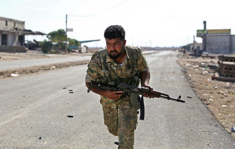 A Turkish-backed Syrian fighter runs along a road in Syria's northeastern town of Ras al-Ain in the Hasakeh province along the Turkish border as Turkey and its allies continue their assault on Kurdish-held border towns in northeastern Syria. Ras al-Ain, is the main remaining flashpoint along the border where Kurdish-led SDF have been putting up stiff resistance against Turkish air strikes and shelling for almost a week. AFP