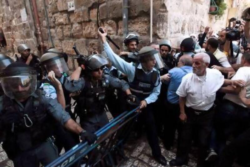 An Israeli policeman (left) shouts at Palestinian demonstrators near Lion's Gate in Jerusalem's Old City, as clashes take place at a nearby compound known to Muslims as Noble Sanctuary and to Jews as Temple Mount.