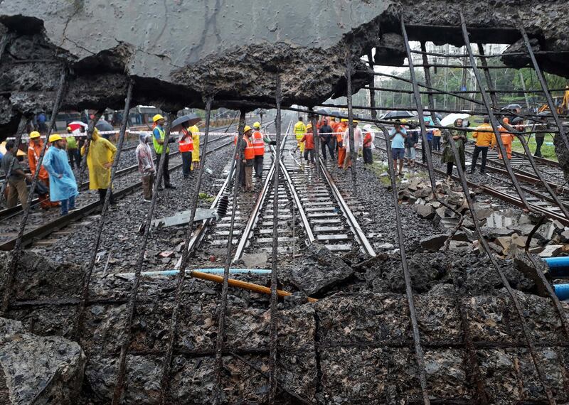 Rescue workers stand at the site of a pedestrian bridge that collapsed at a train station in Mumbai, India. The bridge collapsed Tuesday morning during heavy rains. Rafiq Maqbool / AP Photo
