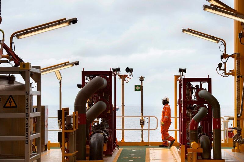 A worker walks on the Kaombo Norte, an oil tanker converted into a FPSO vessel (Floating Production Storage and Offloading), owned by the French Total oil company, on November 8, 2018, about 250km off the coast of Angola in the Atlantic Ocean. Moored in the endless South Atlantic Ocean far off the coast of Angola, the "Kaombo Norte" oil-extraction vessel is a deeply impressive sight -- 330 metres long, with a tower 110 metres high sending a burning flame into the sky. But inside, daily life on the ship is a different matter, with a crew of about 100 sharing narrow passages and confined spaces, living for weeks at a stretch in close quarters 24 hours a day.  / AFP / Rodger BOSCH
