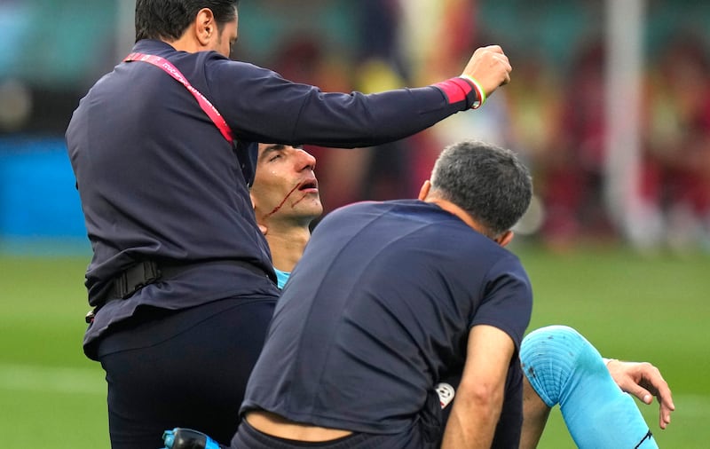 Iran's Beiranvand is attended to by team support staff after being injured. Photo: AP