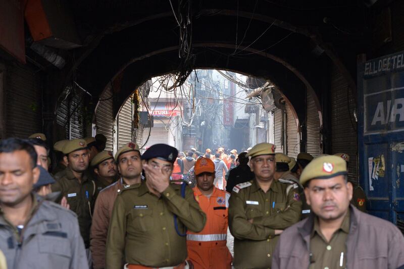 Indian police officers stand guard as rescue workers move toward the site where a fire broke out in New Delhi, India. According to news report, at least 40 people were killed after a  fire broke out at a building in New Delhi's Anaj Mandi area on the morning of 08 December.  EPA