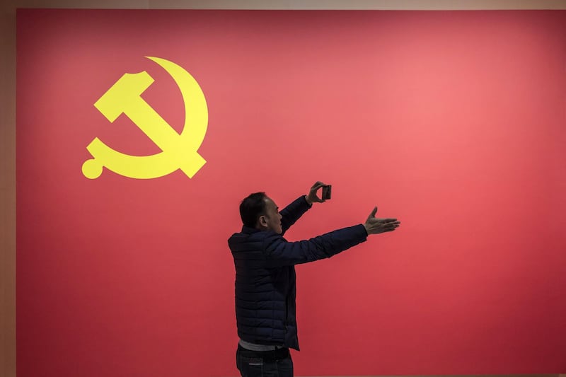 A visitor takes a photograph in front of the Chinese Communist Party flag at the Museum of Contemporary Art & Planning Exhibition in Shenzhen, China. Bloomberg