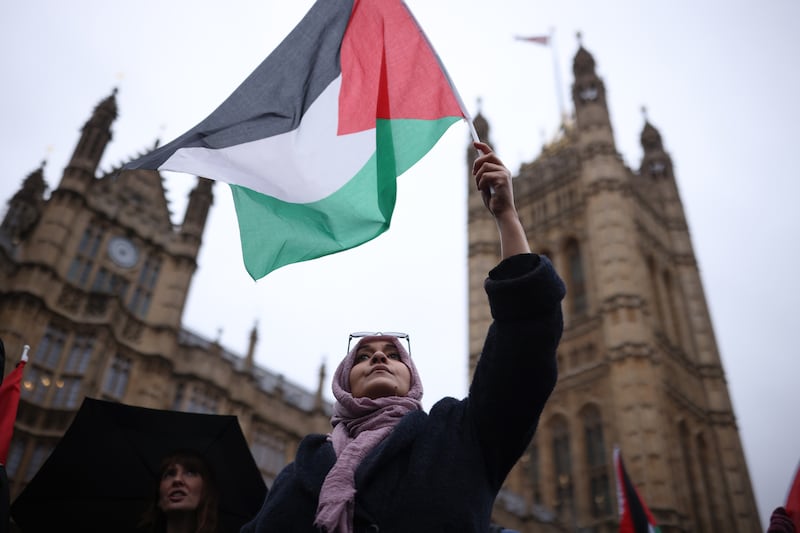 LONDON, ENGLAND - FEBRUARY 21: People wave Palestinian flags during a rally calling for a ceasefire, outside parliament as MPs consider a motion on Gaza on February 21, 2024 in London, England. Westminster held a second vote on calling for a ceasefire this week. The Scottish National Party (SNP) have returned the motion after using the King's Speech debate to push for an immediate ceasefire in Gaza in November 2023. This move led to several Labour frontbenchers resigning following their support for the SNP amendment. (Photo by Dan Kitwood / Getty Images)