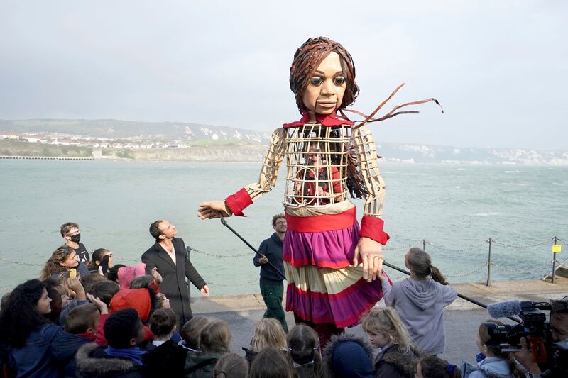 Little Amal, a 3. 5-meter-tall puppet representing a Syrian refugee girl aged 9, arrives at Folkestone Beach in Kent. AP Photo