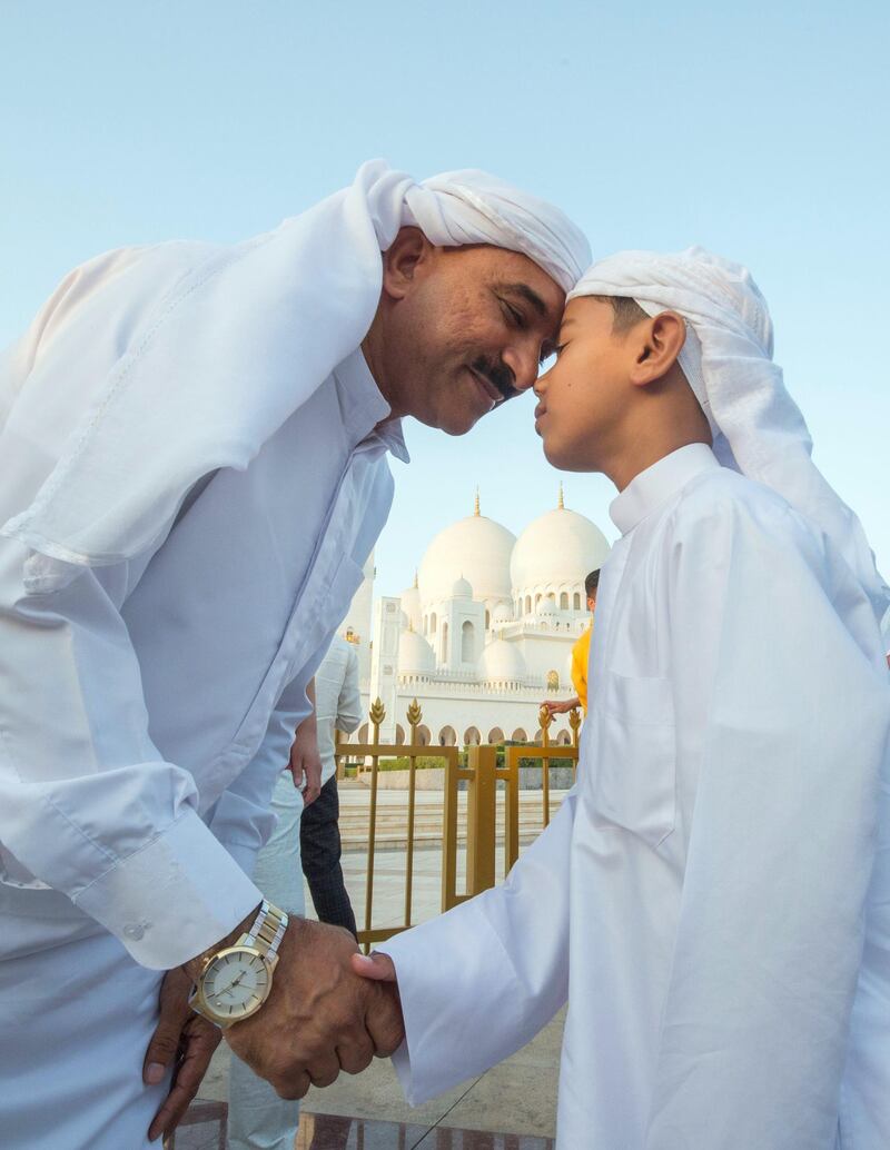 Abu Dhabi, UNITED ARAB EMIRATES - A father and his son greet each other after performing morning prayers on the first day of Eid-Al Fitr at the Sheikh Zayed Grand Mosque.  Leslie Pableo for The National