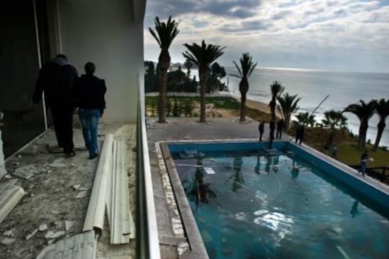 People walk on the balcony overlooking the pool as they visit the burnt and looted house that belonged to the nephew of ousted Tunisian President Zine El Abidine Ben Ali in Hammamet, some 60 kms south-east of Tunis, on January 19, 2011. Hundreds of people protested in the centre of Tunis on January 19, calling for the government to resign and for the abolition of the RCD, the former ruling party under Tunisia's authoritarian regime.    AFP PHOTO / MARTIN BUREAU