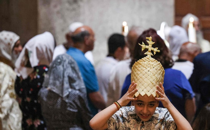 A young Coptic Orthodox Christian wears a hat made of knitted palm fronds as worshippers circle the Edicule at the Church of the Holy Sepulchre in Jerusalem, the place where it is believed Jesus Christ was buried. AFP