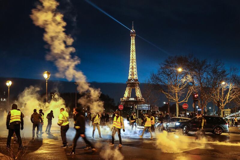Demonstrators of the French "yellow vests" (gilets jaunes) throws tear gas canisters back at police in Paris. AFP