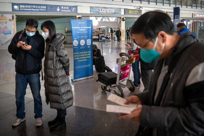 Travellers fill out online electronic health declaration forms before boarding a flight at Beijing Airport. AP