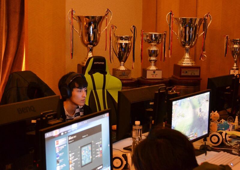 This photo taken on November 28, 2017 shows LGD Gaming players, with their trophies on display, practicing at the one of the team's villas in Shanghai. 
The drive to get eSports into the Olympics threatens to divide professional gaming, pitting those thirsty for global recognition against the traditionalists who fear the sport will lose its soul. / AFP PHOTO / PETER STEBBINGS