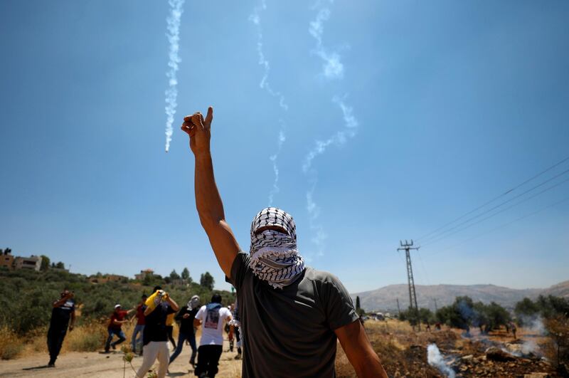 A Palestinian demonstrator gestures as Israeli forces fire tear gas during a protest  in the Israeli-occupied West Bank. Reuters