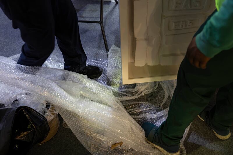 Crew remove artwork from bubble wrap as the opening deadline approaches