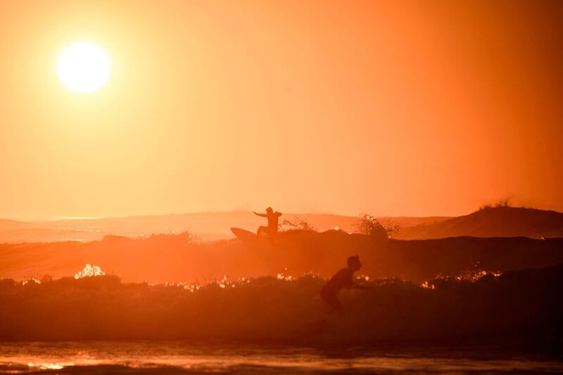 Surfers ride waves during sunset in Bidart, southwestern France. AFP
