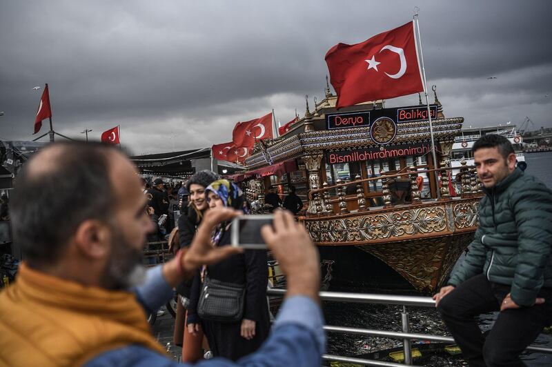 People take pictures next to fish and bread vendors near the Golden Horn in Istanbul's Eminonu district. AFP