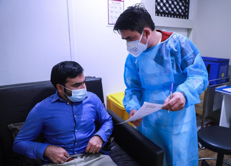 Abu Dhabi, United Arab Emirates, December 13, 2020.   Doctors and UAE residents get Covid-19 vaccinated at the Burjeel Hospital, Al Najdah Street, Abu Dhabi.  Saqib Ali reads some forms before signing and getting his vaccination.
Victor Besa/The National
Section:  NA