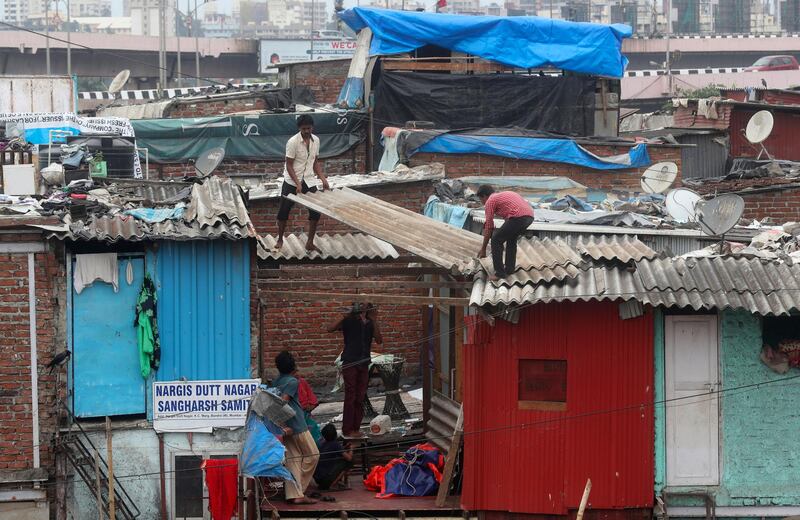 People fix the rooftop of their houses at a slum in Mumbai, India. AP Photo