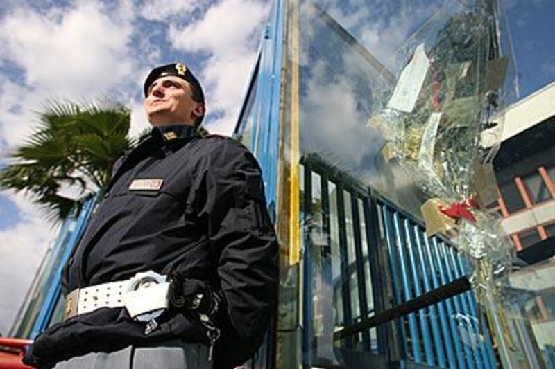 An Italian police officer stands beside flowers left outside the Stadio Angelo Massimino laid in memory of Filippo Raciti, the policeman who died during rioting in 2007.