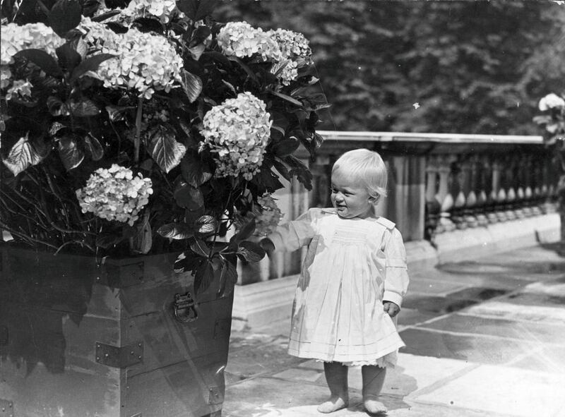 July 1922:  At one year old, Prince Philip of Greece shows an interest in things floral.  (Photo by Topical Press Agency/Getty Images)