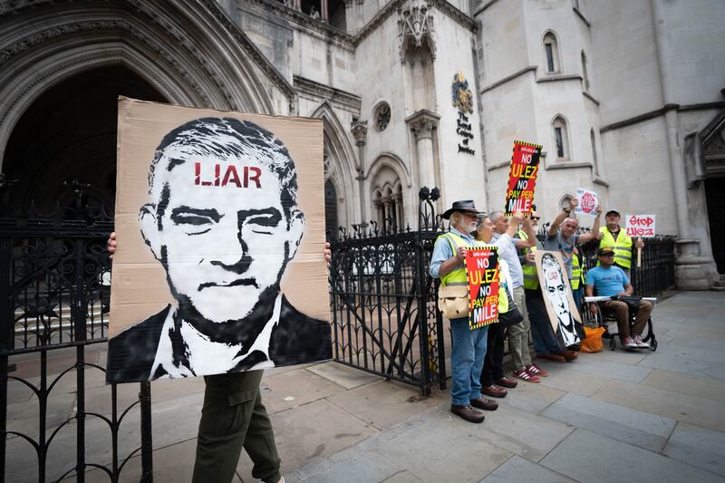 Campaigners against Ulez hold a placard depicting London mayor Sadiq Khan outside the Royal Courts of Justice. PA                                                                   