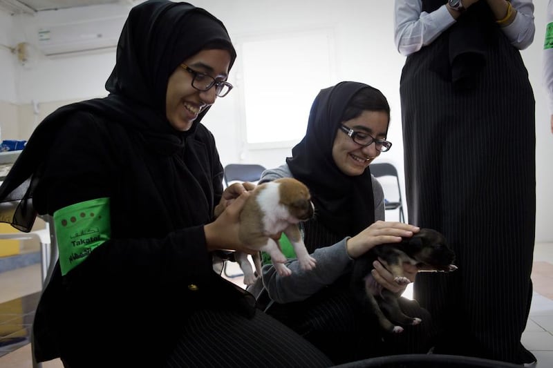 Jawaher Rashid, and Asma Omar, hold puppies. Dogs are taboo, particularly because they are often considered to be ritually unclean.