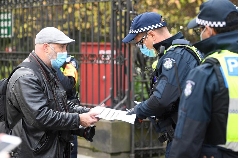 A press photographer has his work permit checked by police during an anti-lockdown protest in Melbourne, Australia.  EPA