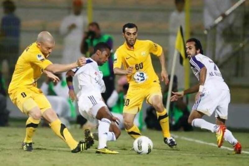 Al Ain’s Fawzi Fayez, centre, shields the ball from Al Wasl defenders in last night’s match. Mike Young / The National