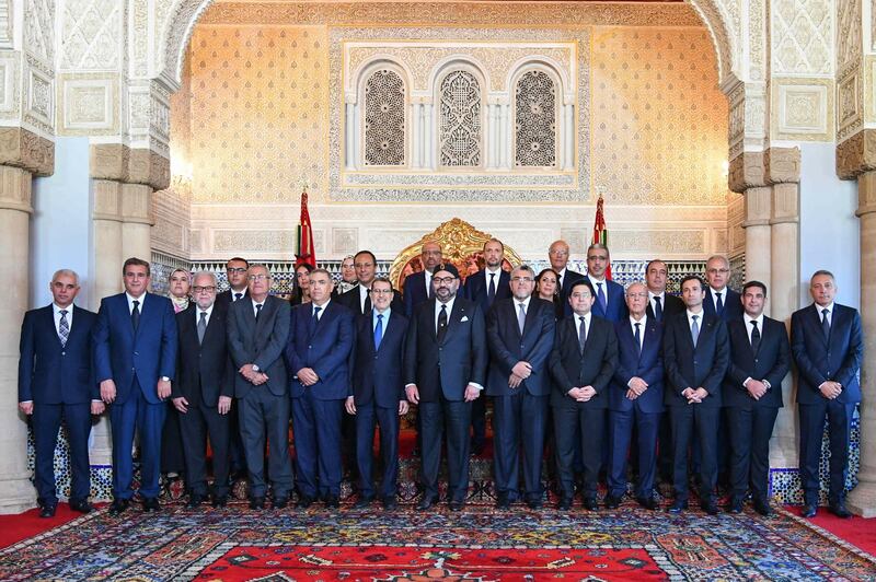 In this Wednesday, Oct. 9, 2019 photo provided by the Moroccan Royal Palace, Morocco's King Mohammed VI, center, and Morocco Prime Minister, Saad Eddine el-Othmani, to his right, poses for a photo with the new Moroccan cabinet. Morocco has reshuffled its government, cutting the number of ministers and junior ministers from 41 to 24. (Moroccan Royal Palace via AP)