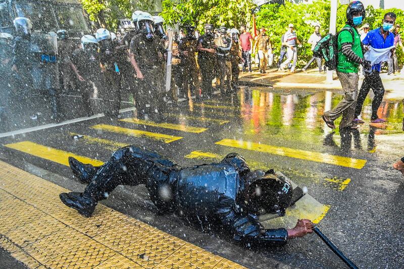 An officer falls as police use water cannons to disperse anti-government protests during a demonstration in Colombo, Sri Lanka. AFP