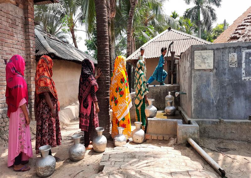 Women wait their turn to fill water at a collection point near their homes in Bangladesh
