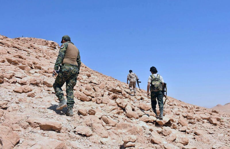 This photo released on Saturday, Sept 2, 2017 by the Syrian official news agency SANA, shows Syrian troops and pro-government gunmen advancing up a hill in the eastern city of Deir el-Zour, Syria. Opposition activists and Syrian state media say government forces are close to breaking a nearly three-year siege imposed by the Islamic State group on parts of the provincial capital of the oil-rich province of the same name. (SANA via AP)