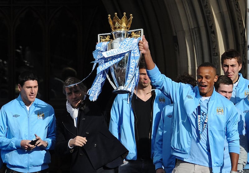 Manchester City's Belgian midfielder Vincent Kompany (R) and manager Roberto Mancini hold the trophy as they celebrate becoming English Premier League champions in a parade leaving from Mancheter Town Hall in Manchester, north-west England on May 14, 2012. Manchester City beat their rivals Manchester United on goal difference to be crowned champions on the final day of the season with a 3-2 victory over Queens Park Rangers.     AFP PHOTO/ ANDREW YATES
