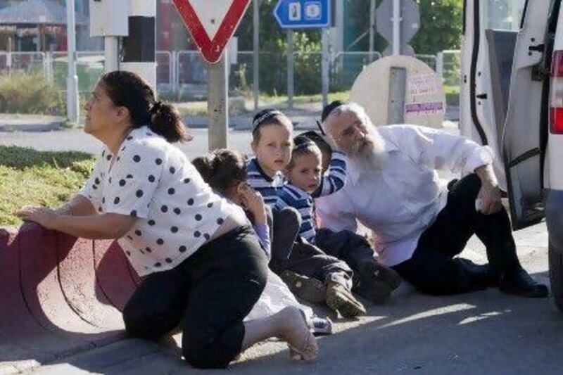 An ultra-Orthodox Jewish man huddles with his three sons and a daughter outside their car in the southern Israeli town of Kiryat Malachai as a red alert sounds signalling a rocket attack.