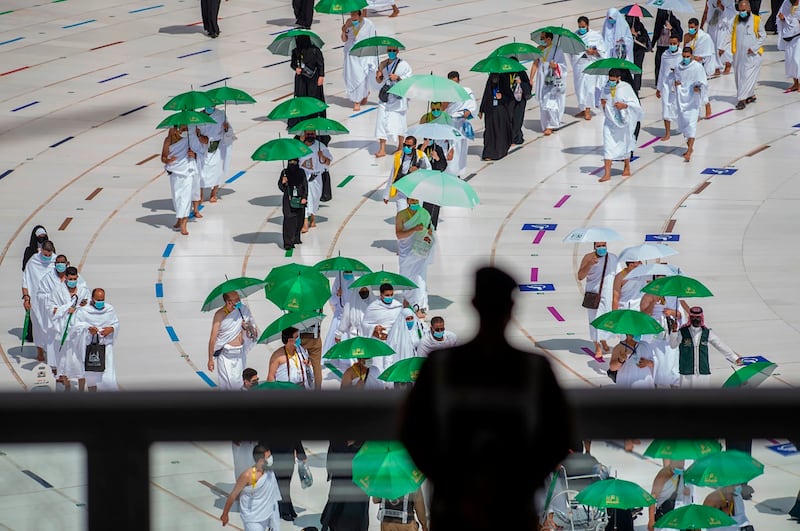 A Saudi security officer watches as pilgrims circumambulate the Kaaba