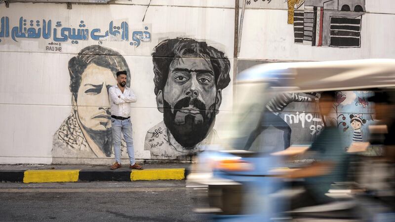 Mustafa Abd standing next to a portrait of one of the icons of the revolution Safa Alsaray. Haider Husseini for The National