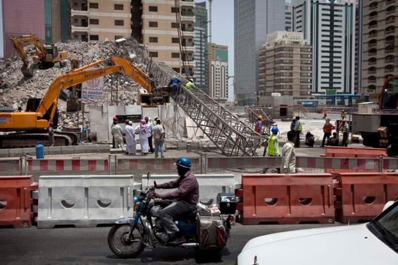 Construction workers work away to clean up remains of a crane that collapsed earlier that morning on Tuesday, July 12, 2011, during the morning rush hour in downtown Abu Dhabi. No one was hurt and only road blocks and the crane itself suffered damages. (Silvia Razgova/The National)

