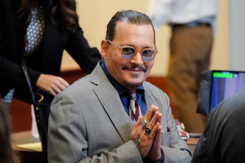 Depp gestures to his fans seated behind him in the courtroom. AP