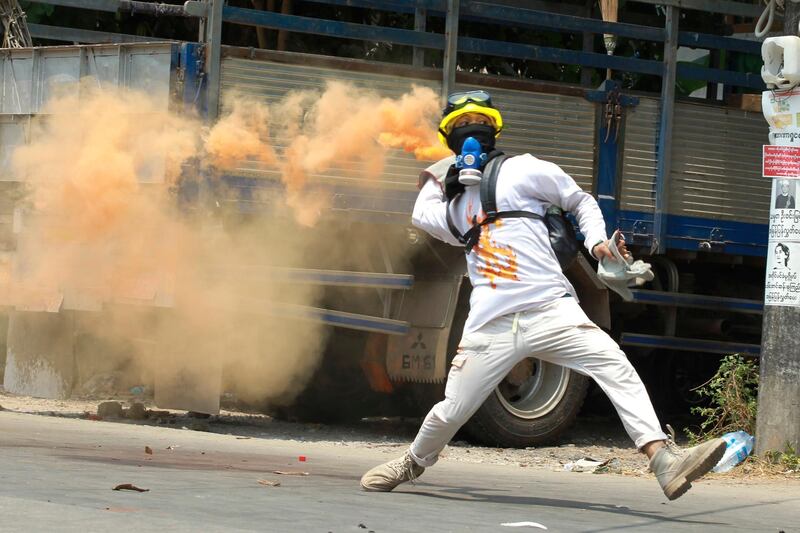 A protester throws a smoke bomb in Thaketa township Yangon. AP Photo