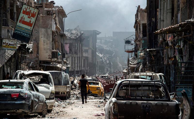 TOPSHOT - A man walks by destroyed vehicles in a street in the Old City of Mosul on July 2, 2017, during the offensive to retake the city from Islamic State (IS) group fighters.
More than eight months since the country's forces launched a gruelling operation to retake Mosul, IS has gone from fully controlling the city to holding a few neighbourhoods on its western side. / AFP PHOTO / Fadel SENNA