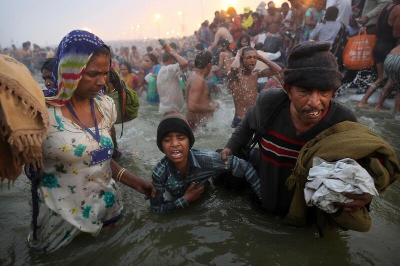 An Indian Hindu boy is reluctantly guided by his parents as they go for a dip fully clothed at Sangam, the confluence of the rivers Ganges, Yamuna and mythical Saraswati, during the royal bath on Makar Sankranti at the start of the Maha Kumbh Mela in Allahabad, India, early Monday, Jan. 14, 2013. Millions of Hindu pilgrims are expected to take part in the large religious congregation that lasts more than 50 days on the banks of Sangam during the Maha Kumbh Mela in January 2013, which falls every 12th year. (AP Photo/Kevin Frayer) *** Local Caption ***  India Maha Kumbh Mela.JPEG-0c588.jpg